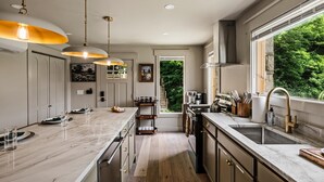 A modern kitchen with a marble countertop, pendant lighting, and a view of greenery outside. - Historic Hodge House|2BD•2BA|King Beds| Sleeps 6 (Banner Elk)