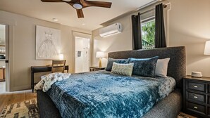 A bedroom with a bed, a ceiling fan, an air conditioning unit, a window with curtains, a bedside table, and a lamp. - Historic Hodge House|2BD•2BA|King Beds| Sleeps 6 (Banner Elk)