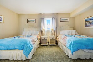 Ein Hotelzimmer mit zwei Betten, einem Fenster mit Vorhängen und Bildern an den Wänden.
