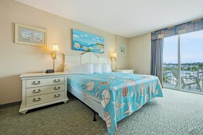 Ein Hotelzimmer mit einem Bett, zwei Nachttischen, einer digitalen Uhr, einem Gemälde und Blick auf einen Yachthafen.