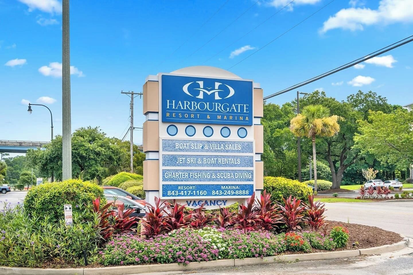 Schild für Harbourgate Resort & Marina mit Annehmlichkeiten wie Bootsliege- und Villenverkäufen, Jetski- und Bootsverleihen sowie Charterfischerei und Tauchaktivitäten.