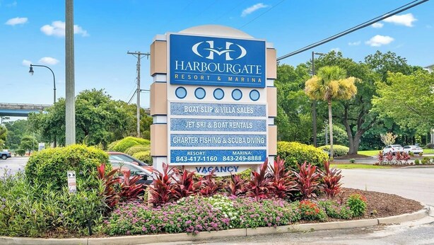 A sign for Harbourgate Resort & Marina with amenities like boat slip & villa sales, jet ski & boat rentals, and charter fishing & scuba diving. - Waterfront Condo | Harbourgate Marina Views (North Myrtle Beach)