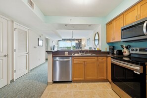 A modern kitchen with stainless steel appliances, wooden cabinets, and a view to the outside. - Waterfront Condo | Harbourgate Marina Views (North Myrtle Beach)