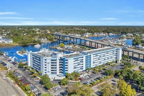A multi-story hotel with a parking lot and a marina with boats. - Waterfront Condo | Harbourgate Marina Views (North Myrtle Beach)