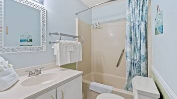 A bathroom with a sink, mirror, towel rack, shower, and toilet.