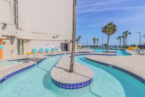 Ein Swimmingpool mit einer runden Whirlwanne, Liegestühlen und Palmen.