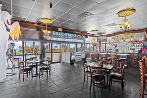 Een restaurant met een strandthema, terras, bar en uitzicht op het strand.