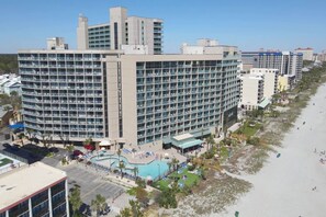Ein Hotel mit mehreren Etagen, einem Schwimmbad und einer Strandlage.