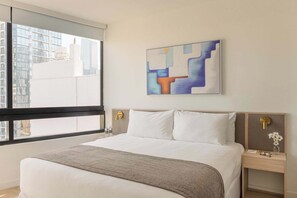 A hotel room with a large bed, a window with a view of buildings, a painting on the wall, and a nightstand with a lamp. - City Dreams Sauna, Rooftop Pool & Parking (Miami)