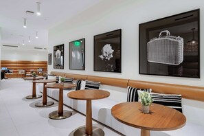 A modern hotel lobby with a seating area, wooden tables, and artwork on the walls. - City Dreams Sauna, Rooftop Pool & Parking (Miami)