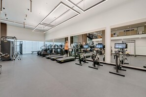 A modern gym with various cardio machines, mirrors, and a person exercising. - City Dreams Sauna, Rooftop Pool & Parking (Miami)