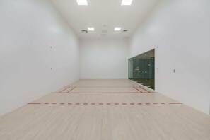 Ein geräumiger Squashplatz im Innenbereich mit Holzboden und roten Spiellinien.