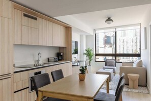 A modern kitchen with a dining area, large windows, and a view of the city. - City Dreams Sauna, Rooftop Pool & Parking (Miami)