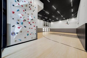 Eine Kletterwand mit verschiedenen Griffen und einem Basketballkorb in einem modernen Innenbereich.