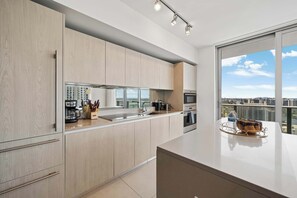 Eine moderne Küche mit einem großen Fenster, einer Kaffeemaschine und Blick auf die Stadt.
