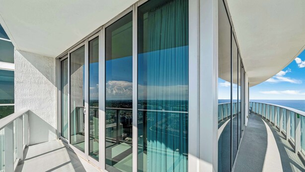 En moderne balkon med glasdøre og havudsigt.