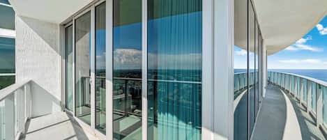 A modern balcony with glass doors and a view of the ocean.