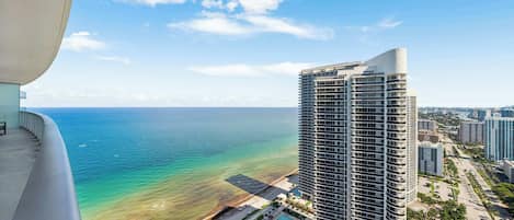A high-rise hotel with a pool, ocean view, and urban surroundings.