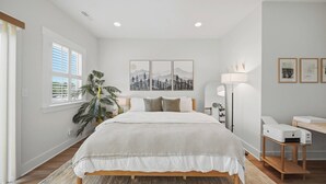 A bedroom with a bed, a large potted plant, a desk with a printer, and framed pictures on the wall. - Elegant 3BR Retreat  close to Hospital & Downtown (East Ridge)