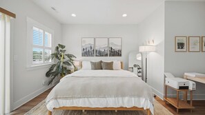A bedroom with a bed, a large potted plant, a desk with a printer, and framed pictures on the wall. - Elegant 3BR Retreat  close to Hospital & Downtown (East Ridge)