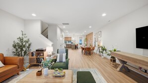 A modern living room with a sofa, coffee table, and plants. There is a staircase leading to another level. - Elegant 3BR Retreat  close to Hospital & Downtown (East Ridge)