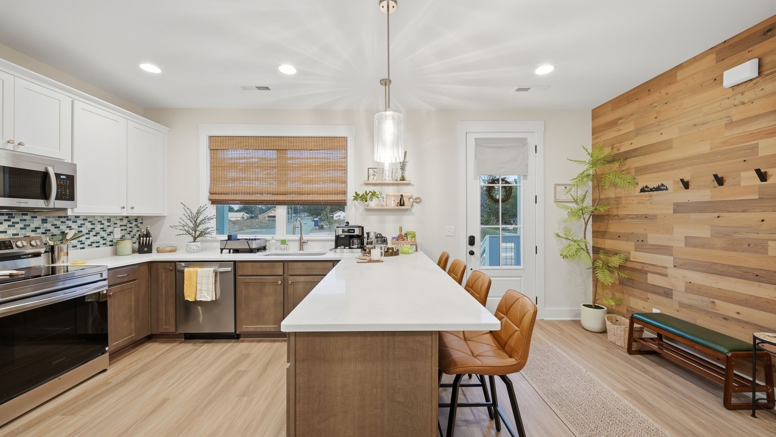 A modern kitchen with a central island, stainless steel appliances, and a wooden accent wall.