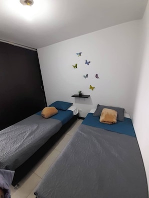 A room with two single beds, a small table with a plant, and butterfly wall decals. - Very Affordable Apartment Just 3' from Parque del Café (Montenegro Province)