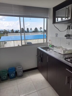 A kitchen with a large window, a sink, cabinets, and three trash bins. - Very Affordable Apartment Just 3' from Parque del Café (Montenegro Province)