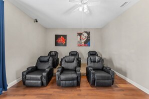 A room with three massage chairs, a ceiling fan, and two posters on the wall.