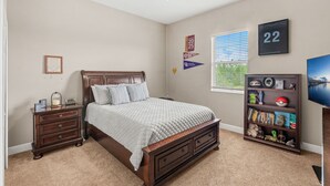 A bedroom with a bed, nightstand, bookshelf, and a ceiling fan. - 2820 Corey Road (Malabar)