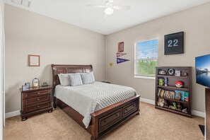 A bedroom with a bed, nightstand, bookshelf, and a ceiling fan. - 2820 Corey Road (Malabar)