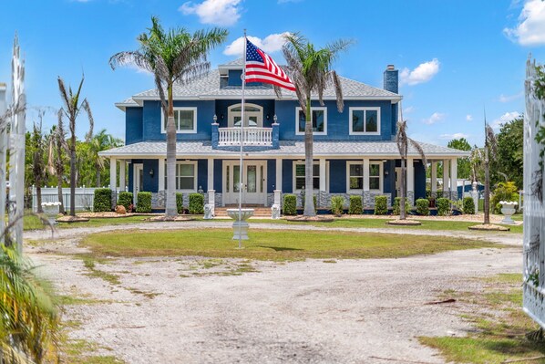 A large two-story house with a front porch, a flagpole with an American flag, and a well-maintained lawn.