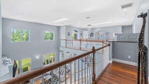 A spacious interior with a wooden staircase, multiple windows, and a view of the outdoors. - 2820 Corey Road (Malabar)