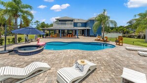 A pool area with lounge chairs, a hot tub, and a large house in the background. - 2820 Corey Road (Malabar)