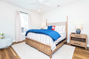 A bedroom with a four-poster bed, a nightstand, a lamp, and a view of the city through the window. - The Grove Getaway at Patterson Place (Oxford)