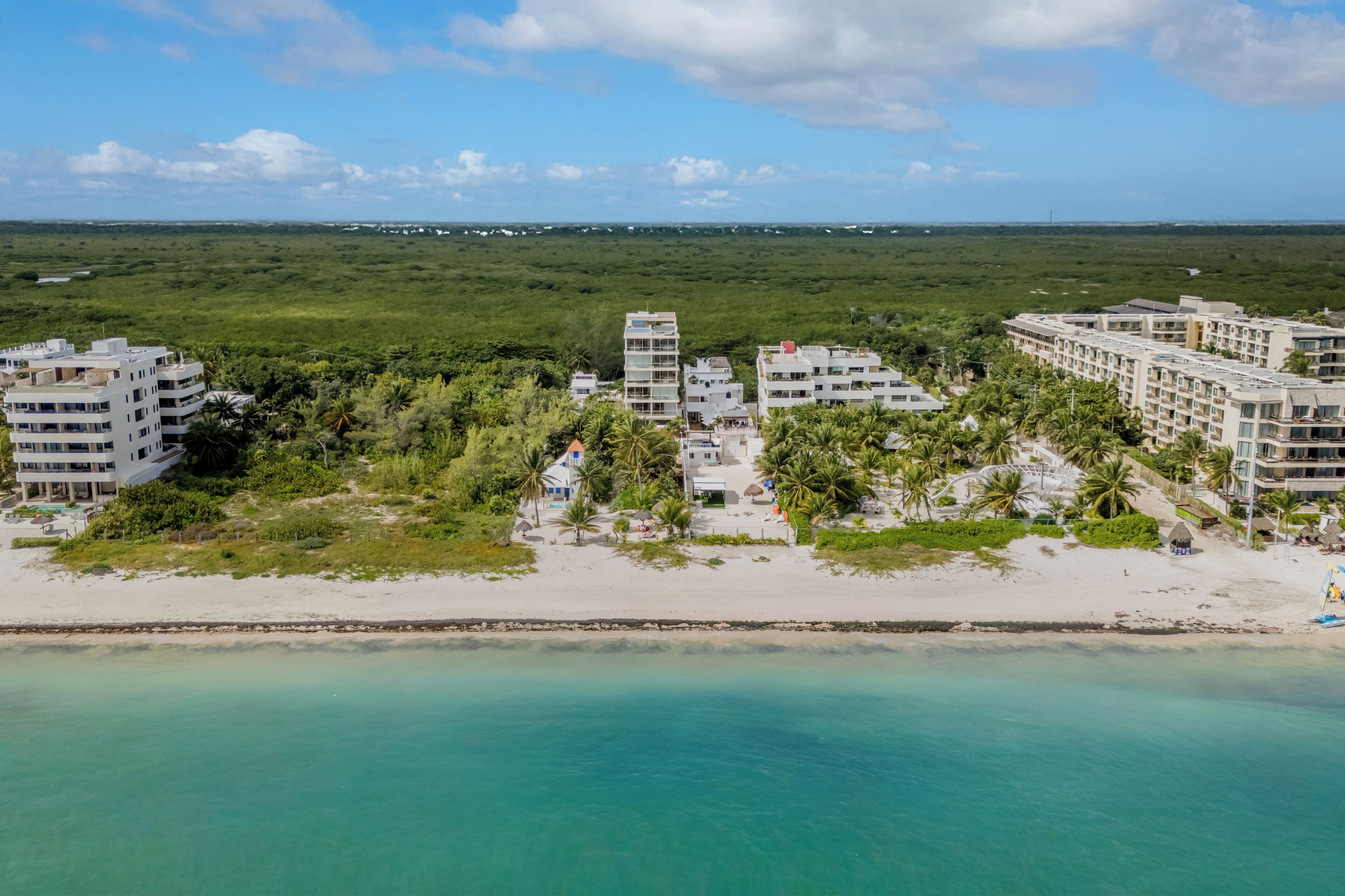 Un hôtel situé sur la côte, composé de plusieurs bâtiments, avec une plage et une vue sur l’océan.