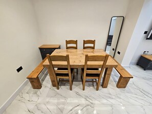 Ein Essbereich mit einem Holztisch und Stühlen, einer kleinen Kommode und einem Spiegel an der Wand.