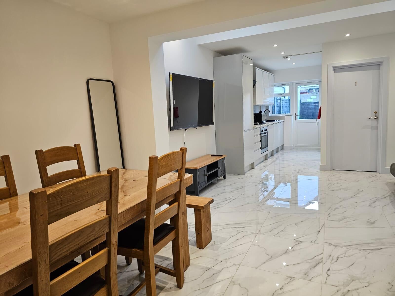 A modern kitchen with white cabinets and a flat-screen TV mounted above the counter.