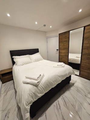 Une chambre d’hôtel moderne avec un grand lit, une armoire en bois et un sol en marbre.