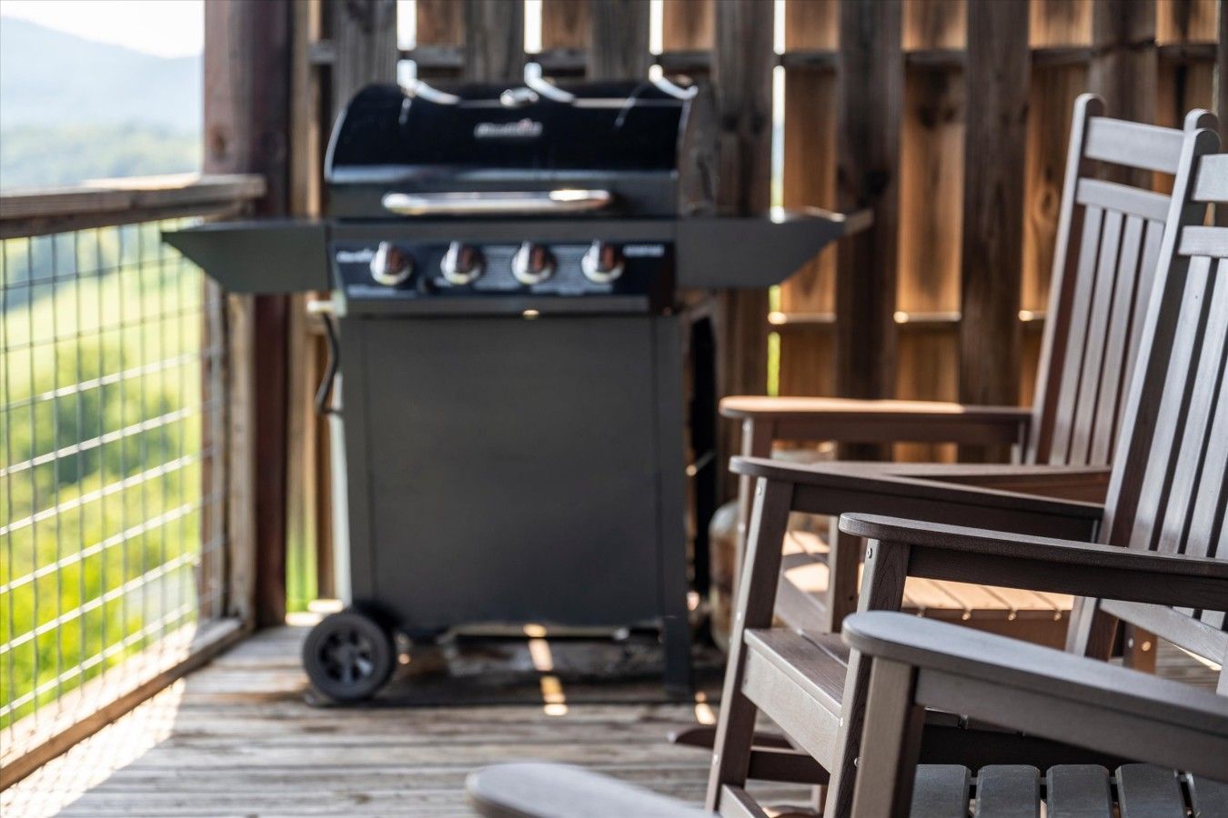 A wooden deck with a barbecue grill and chairs.