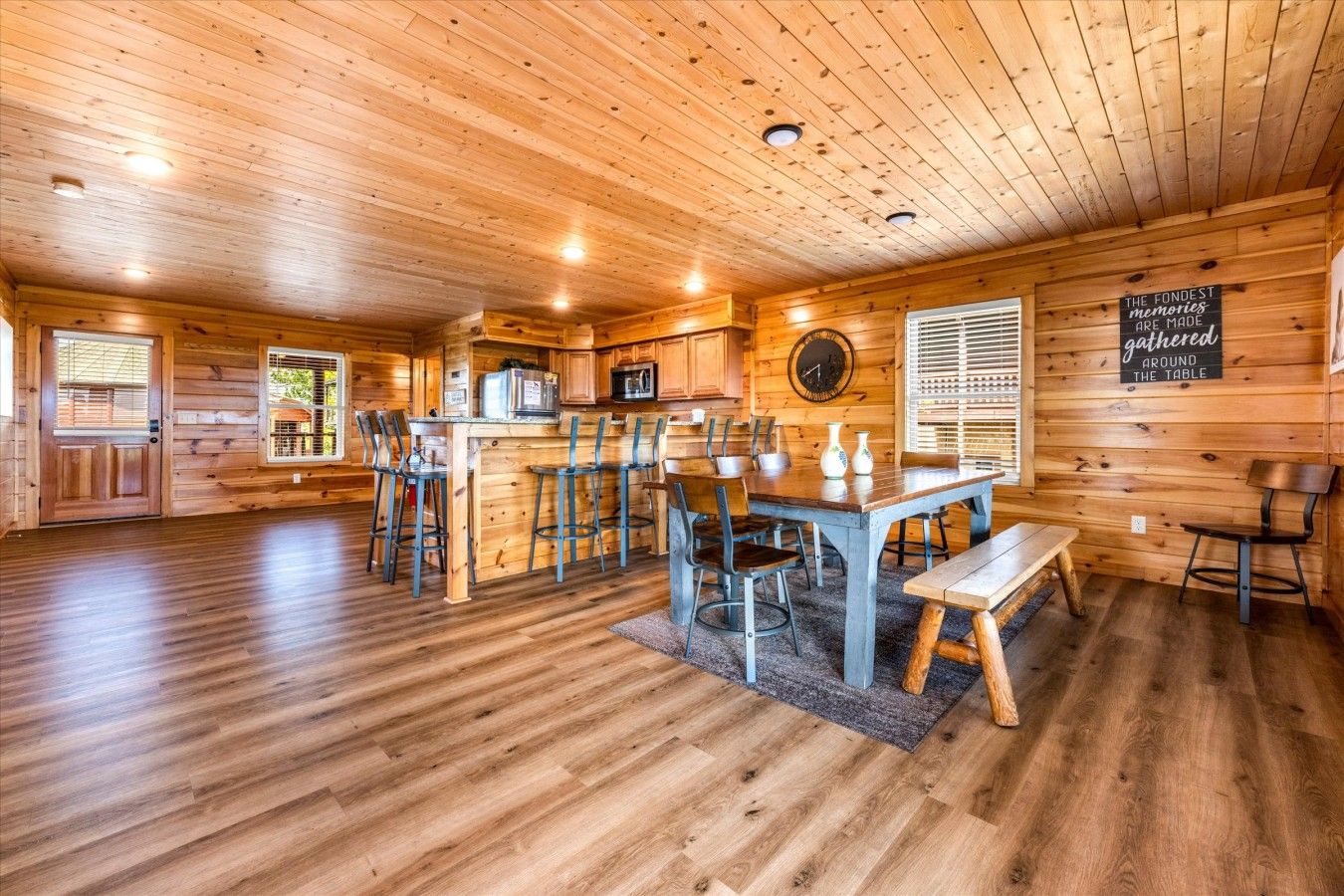 Un intérieur en bois comprenant un coin repas, une cuisine et une horloge murale.