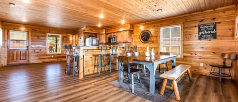 Un interior de madera con comedor, cocina y un reloj en la pared.