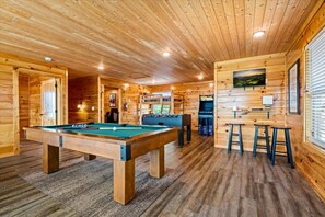 Un interior de fusta amb taula de bitlles, zona de bar i jocs recreatius.