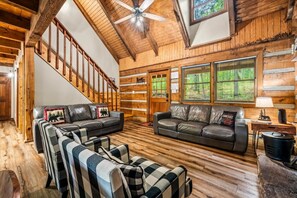A log cabin interior with a staircase, leather sofas, and a fireplace. - 5 Mins to Pigeon Forge! Hot Tub*Game Room*Fire Pit (Pigeon Forge)