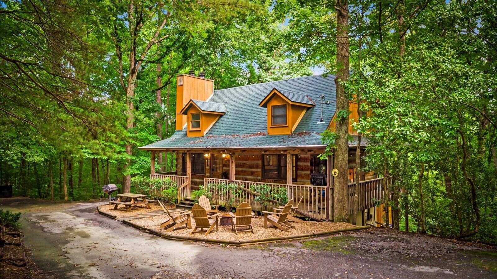 A cabin with a porch, outdoor seating, and a dirt path leading to it.