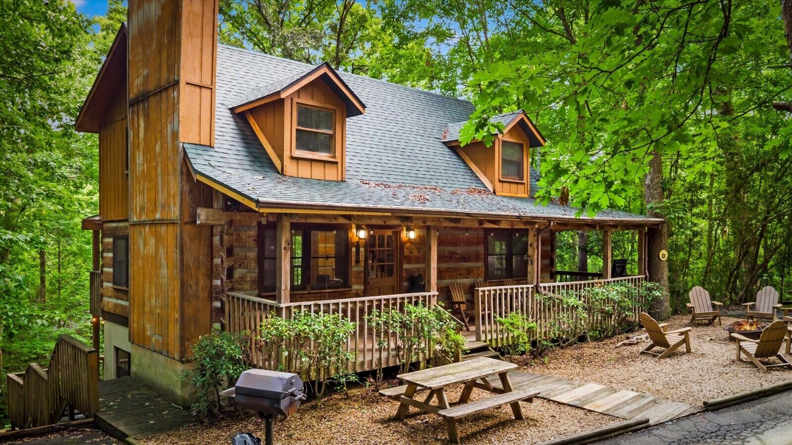 A cabin with a porch, outdoor seating, and a fire pit.