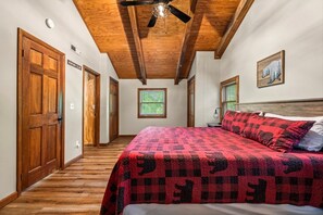 Un dormitorio con una cama grande, vigas de madera en el techo, una ventana y una puerta.
