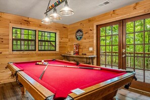A pool table with balls, a wooden wall with a sign, and a door leading to an outdoor area. - 5 Mins to Pigeon Forge! Hot Tub*Game Room*Fire Pit (Pigeon Forge)