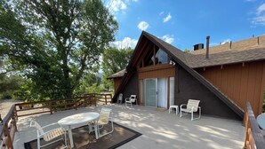 A modern building with a sloped roof, a covered patio with a table and chairs, and a wooden deck. - Mountain Chalet next to Angeles National Forrest and near Hard Rock Casino Tejon (Frazier Park)