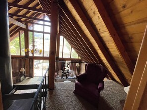 A wooden interior with a high ceiling, a staircase, and a view of the outdoors.